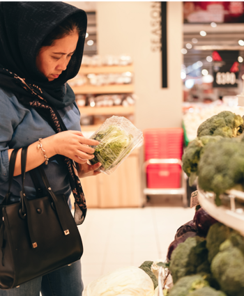 lady in a store picking up vegetables 